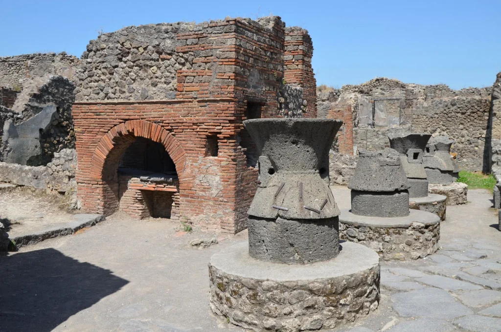 The Bakery (pistrinum) of Popidius Priscus contains four large millstones made from porous lava, traces of a stable, four storage rooms and a large oven which was used for baking the bread.